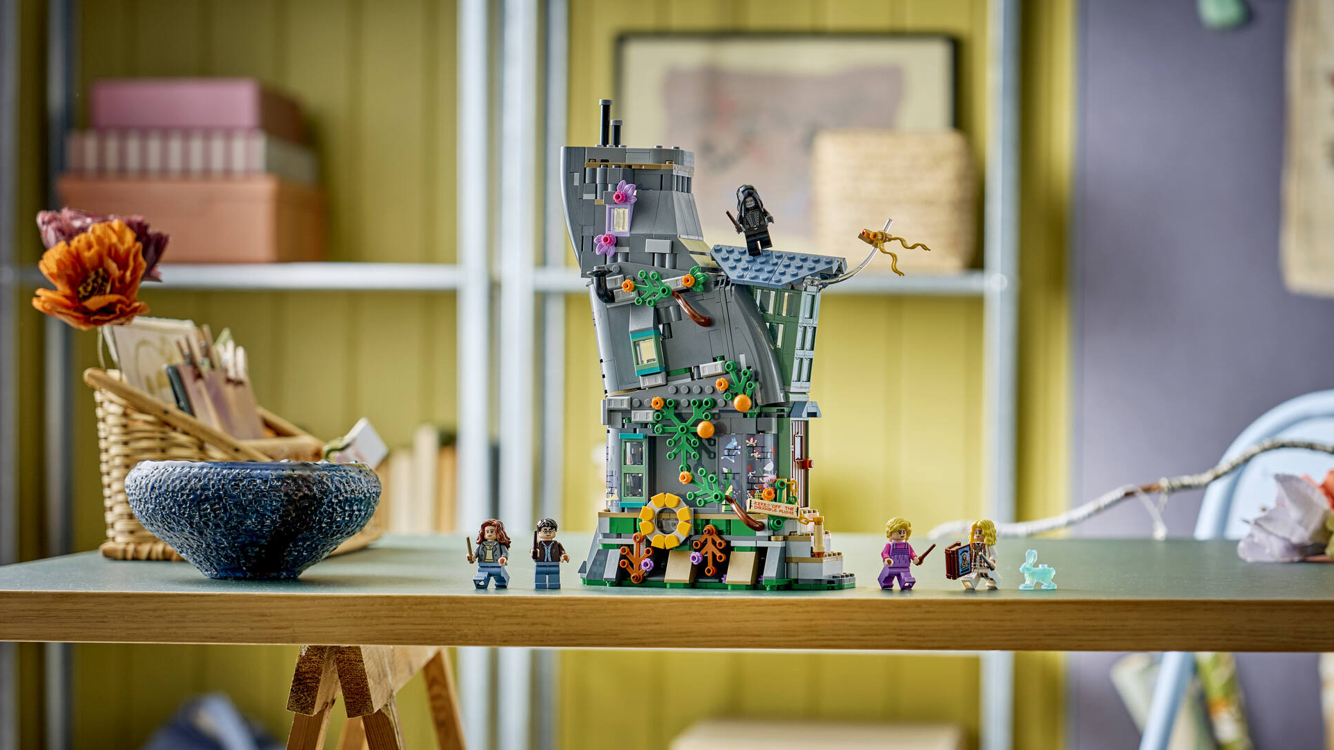 A lopsided Lego house sits on a table alongside minifigures