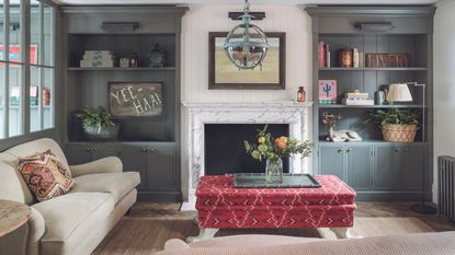Living room with fireplace, footstool, sofas and built in painted gray shelving