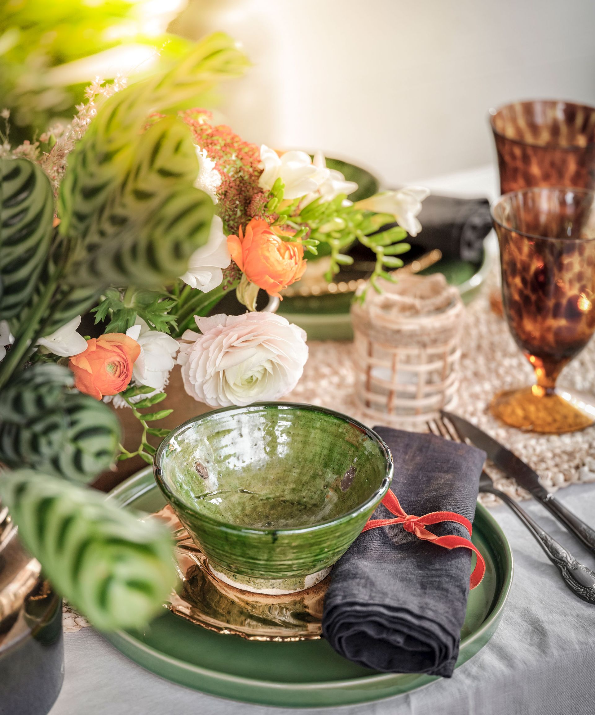 A close-up shot of an al-fresco place setting with green crockery and rattan place mats