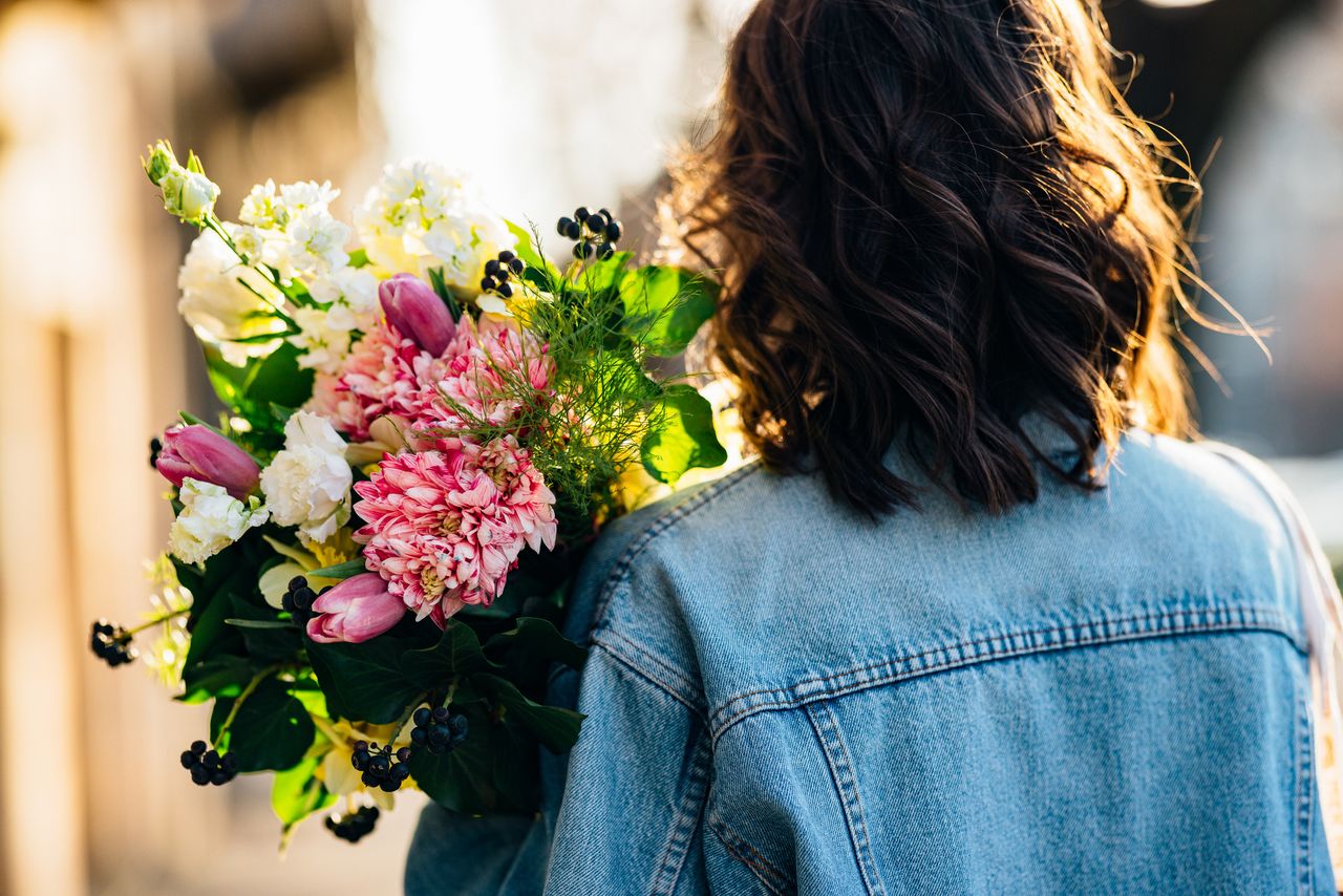 Back view of an anonymous woman with flowers outdoors to illustrate how to romanticise your life