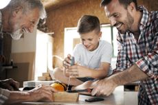 Grandfather ,father and son working at workshop screwing a screw