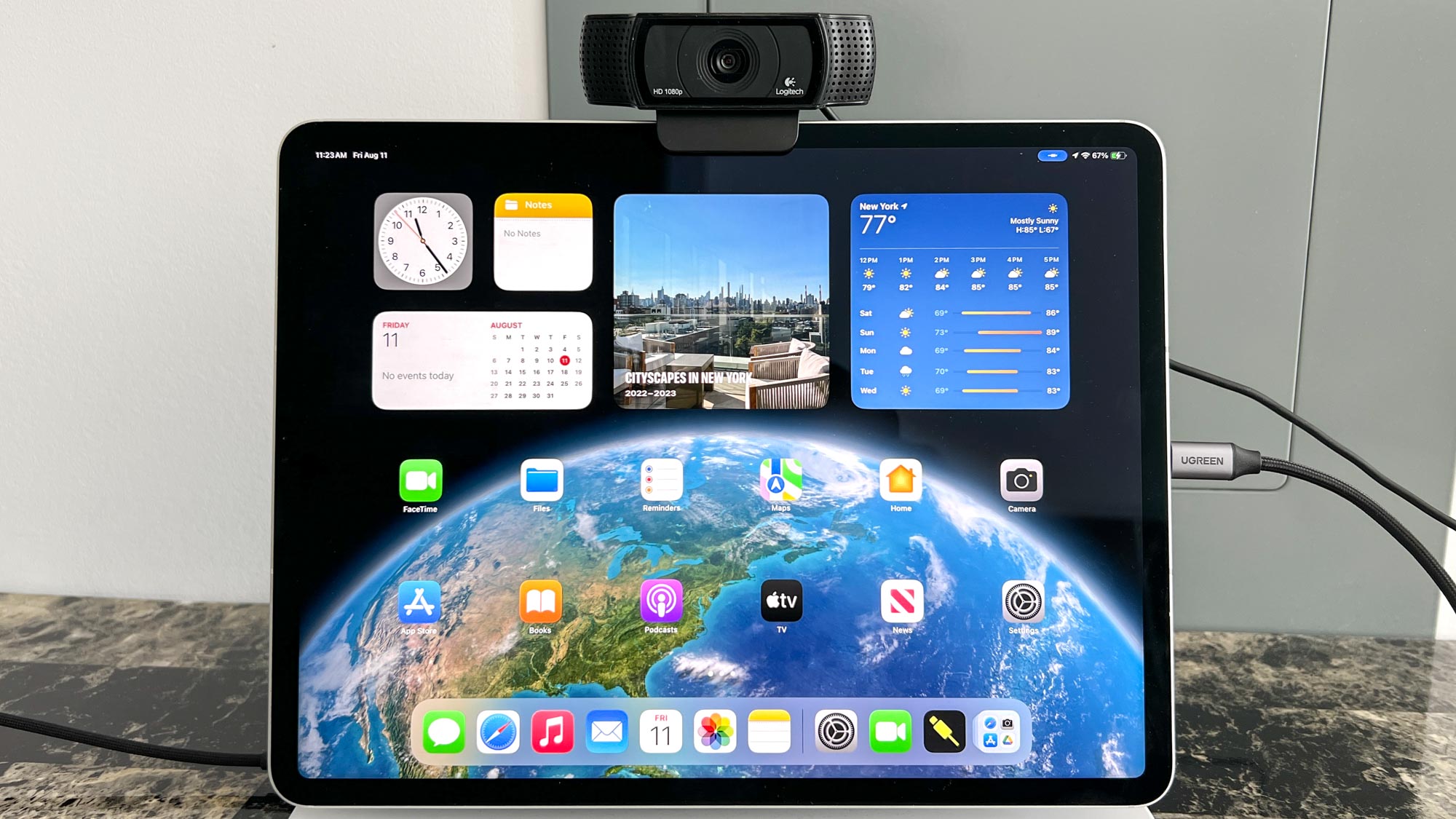 внешняя веб-камера USB, прикрепленная к верхней части iPad Air с клавиатурой Magic Keyboard, показывающая главный экран