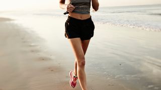 Woman running on beach in a pair of shorts