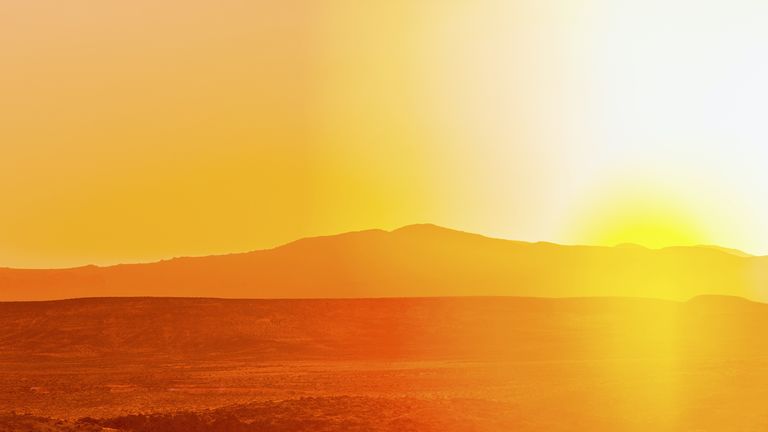 Hot sun casts orange-red glow over a desert