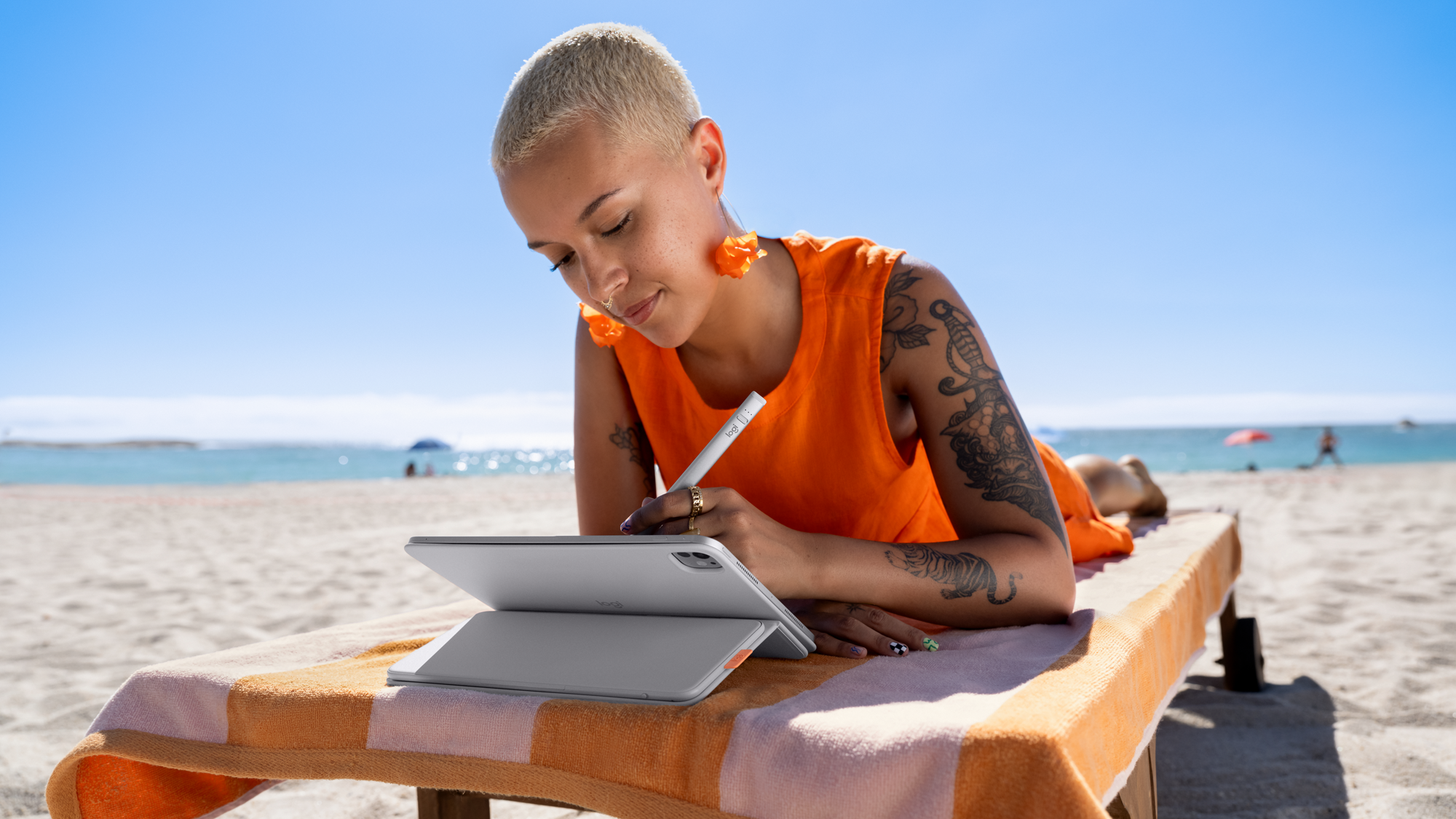A woman on the beach uses a Logitech Flip Folio case with a stylus.
