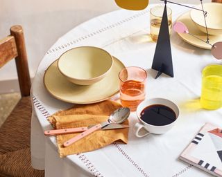 table with cutlery, bowl, plate and mug of black coffee