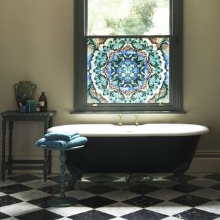 black and white tiled bathroom with colourful window film and black bath