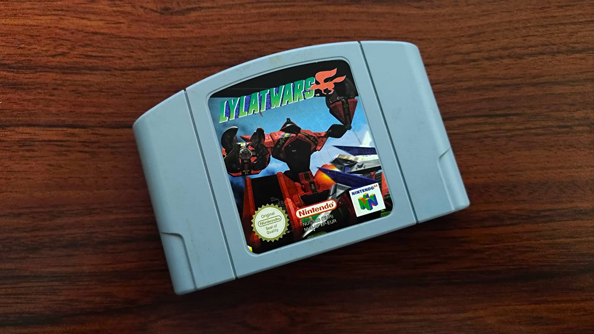 Lylat Wars (Star Fox 64) cartridge on woodgrain desk.