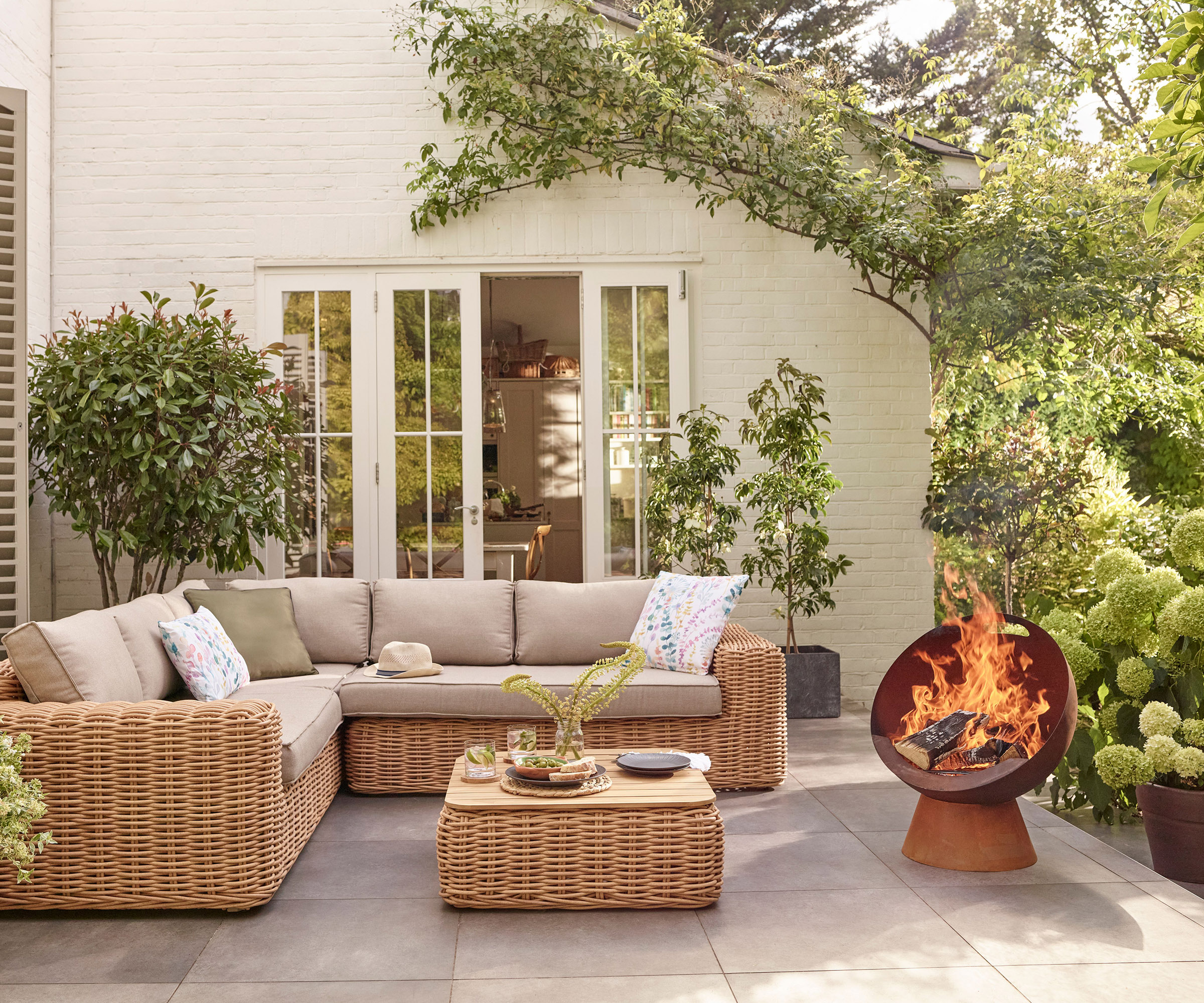 An outdoor sofa on a patio with a lit firepit