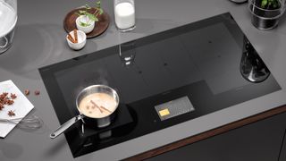 Modern black indiction hob with saucepan warming milk with stair anise