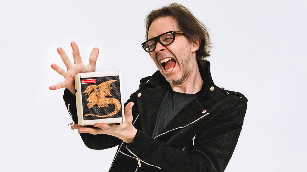 Paul Gilbert holds his new signature Positive Grid Spark Mini amp