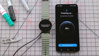 Samsung Galaxy Watch 7 next to a Samsung Galaxy S24 smartphone showing the final stages of the watch setup process 