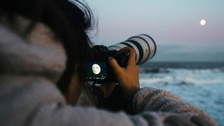 a person using a camera to photograph the moon