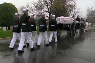 John Glenn's flag-draped casket is transported to his grave site at Arlington National Cemetery by a caisson procession on April 6, 2017.