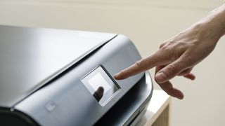 A hand using a printer's touchscreen