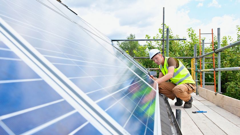 man working on solar panels on roof