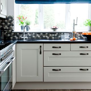 kitchen with white window and white cabinets with black top