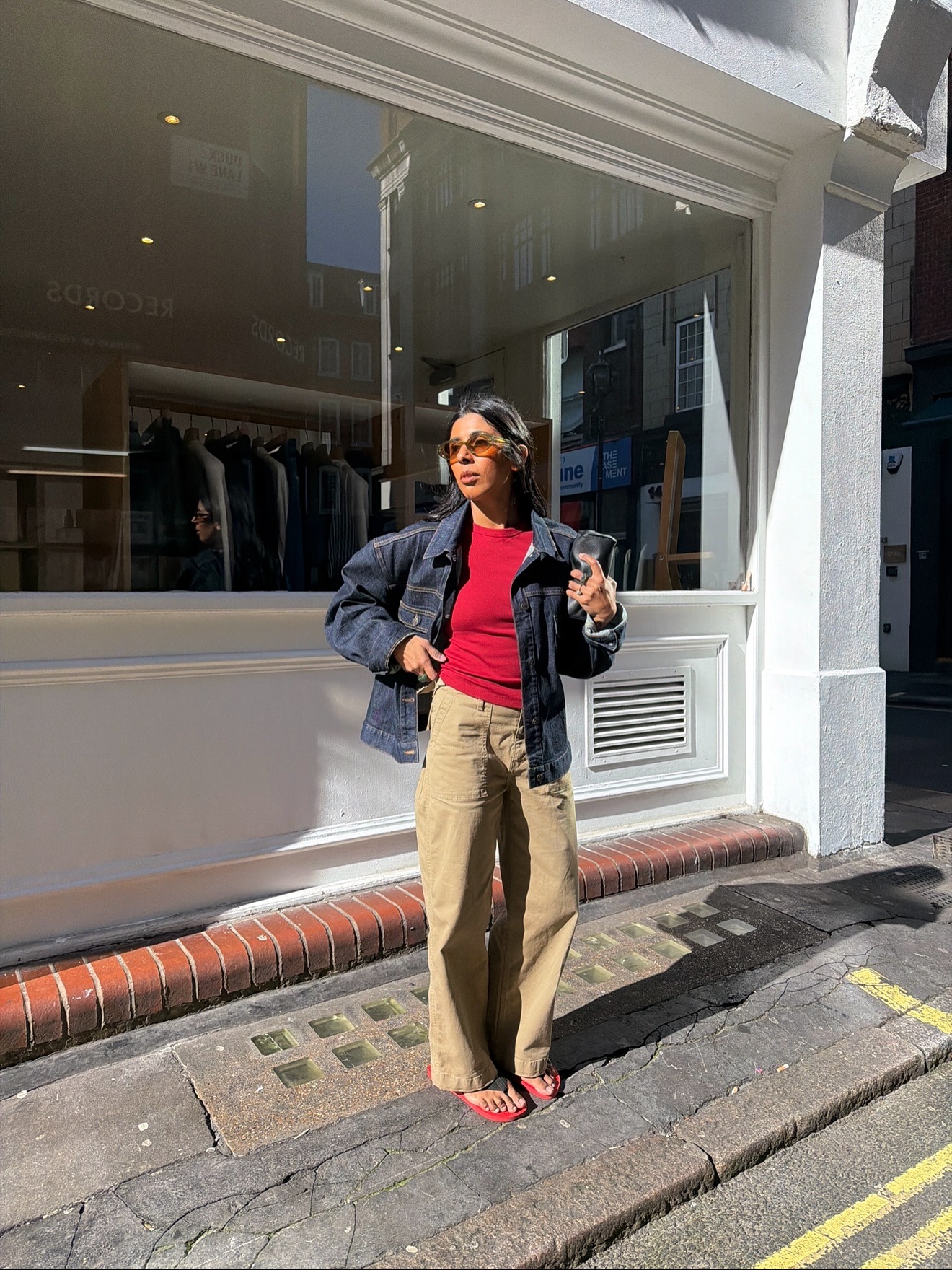 Influencer @monikh wears a red t-shirt with khaki trousers and a dark wash denim jacket.