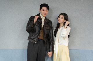 Actors Kim Woo-bin and Bae Suzy make a "fighting" pose while holding hands.