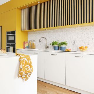 yellow kitchen with granite splashback and wood panel floor