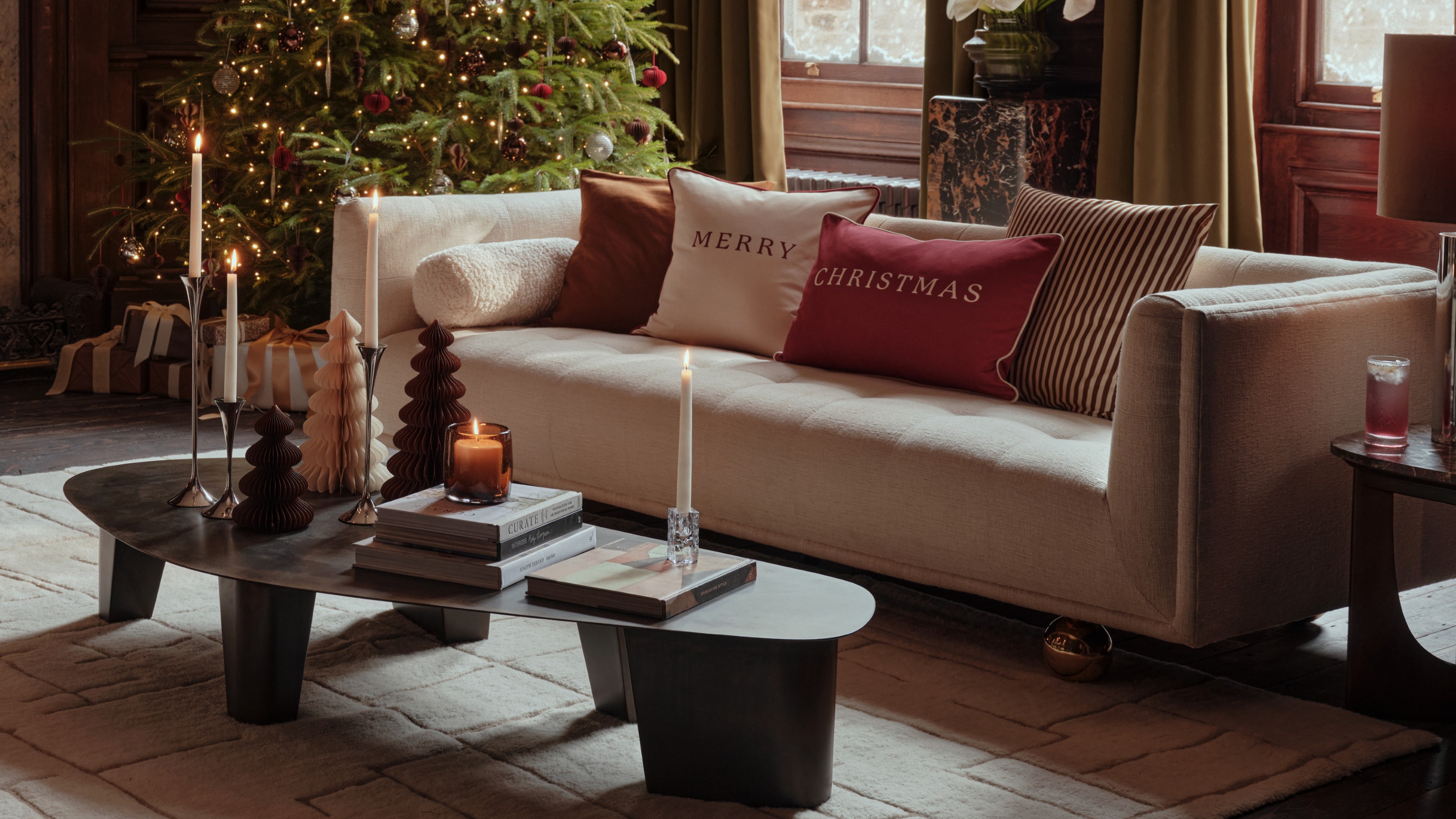 A living room with a cream sofa and a modern coffee table decorated for Christmas