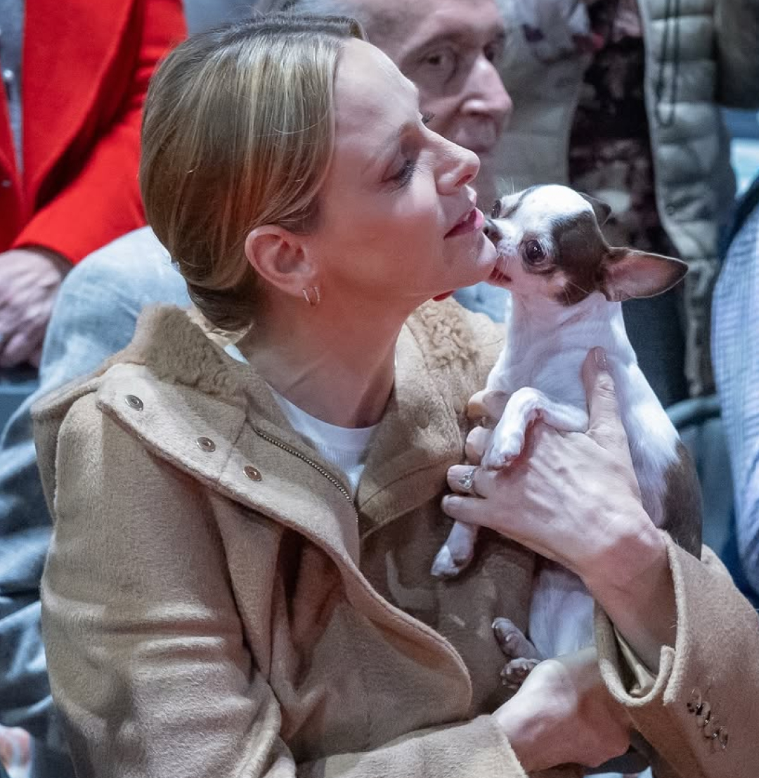 Princess Charlene holding a small dog licking her face