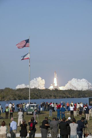 Space shuttle Discovery's liftoff from Launch Pad 39A at NASA's Kennedy Space Center in Florida on a picturesque, warm, late February afternoon is witnessed by news media representatives near the countdown clock at the Press Site.