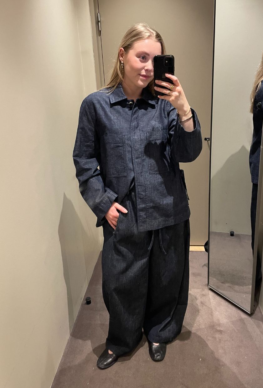 Woman wears denim shirt, denim trousers and ballet flats