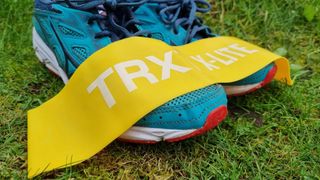 Image shows yellow TRX Strength Bands resting on a pair of running shoes.