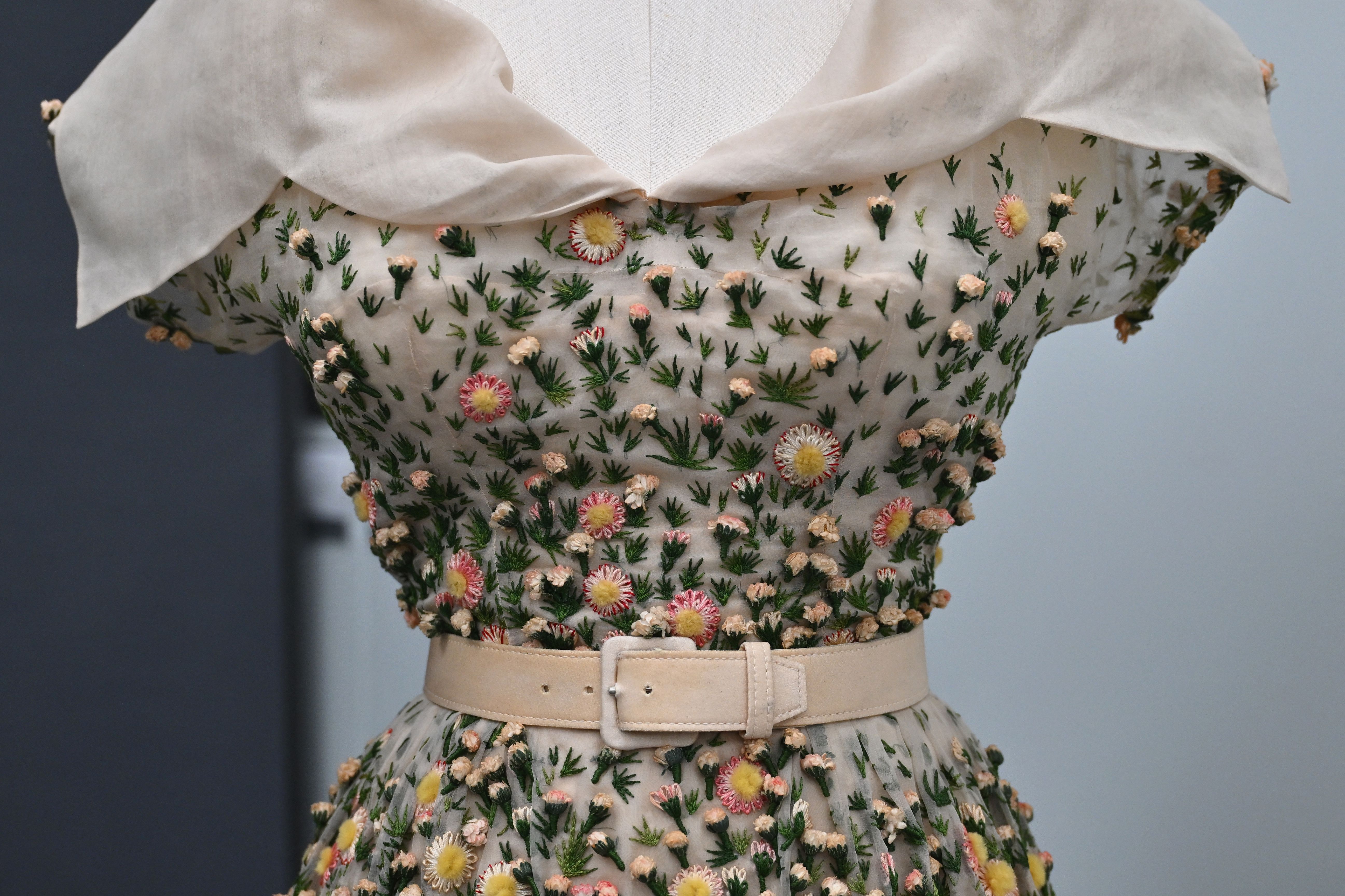 a close-up image of a floral-embroidered dress with a beige belt