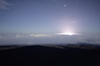 The glow from the ongoing Kilauea volcanic outburst is seen at center-right in this photo captured by the Gemini North Telescope's cloud camera during the night of May 21 to May 22, 2018. The dimmer yellow-green glow just left of center is the town of Hilo.
