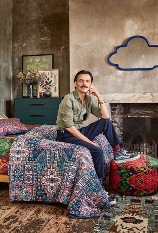 The designer Matthew Williamson sat on a printed bedspread