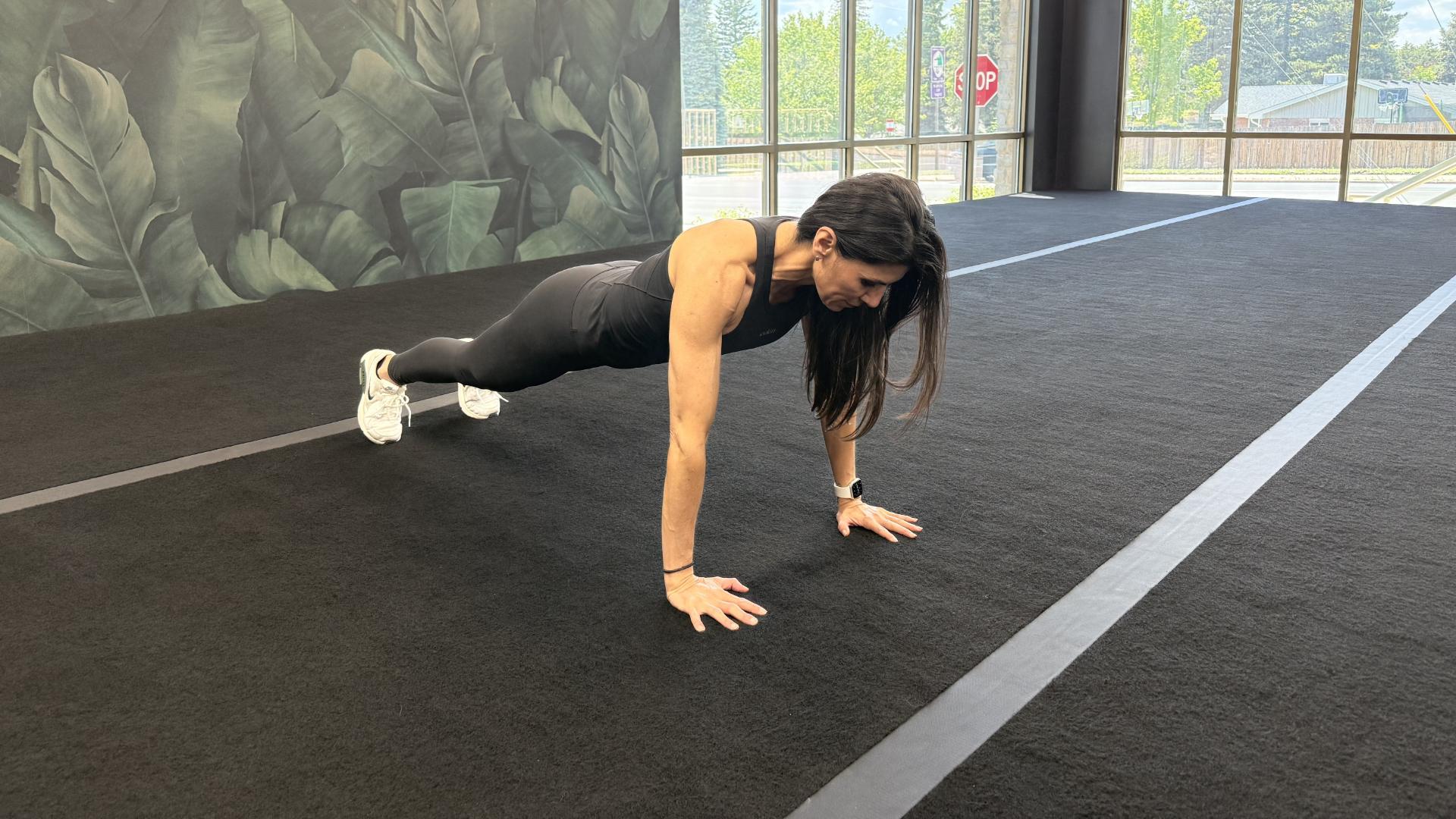 Woman exercising in empty gym space, in the high plank position
