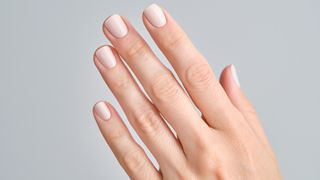 A hand with creamy white nail polish