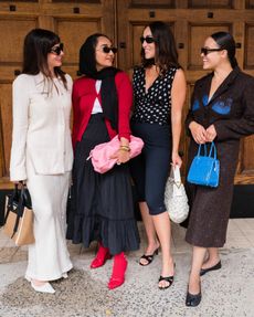 four women looking at each other smiling fashionable
