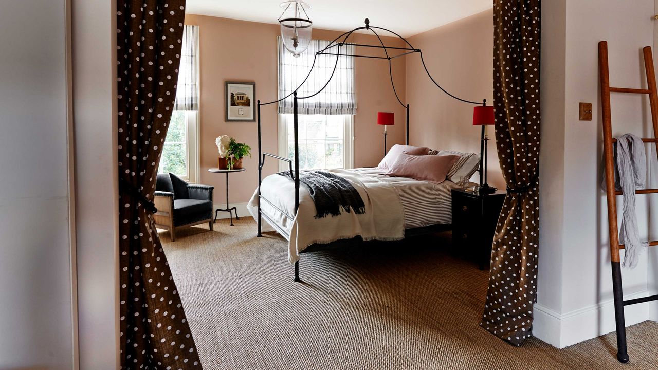 pink bedroom with four poster black bed frame