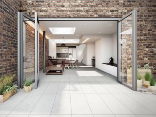 indoor-outdoor Porcelain Tiles in an all-white kitchen extension with bi-fold doors and a white kitchen beyond