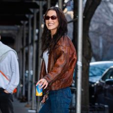 Bella Hadid styles brown Adidas trainers with a brown leather jacket.