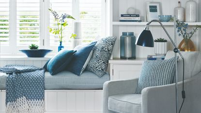 A white and blue livin groom with a window seat and built-in storage around the windows