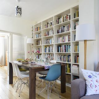 room with white wall book shelves and wooden floor and dining table with chairs