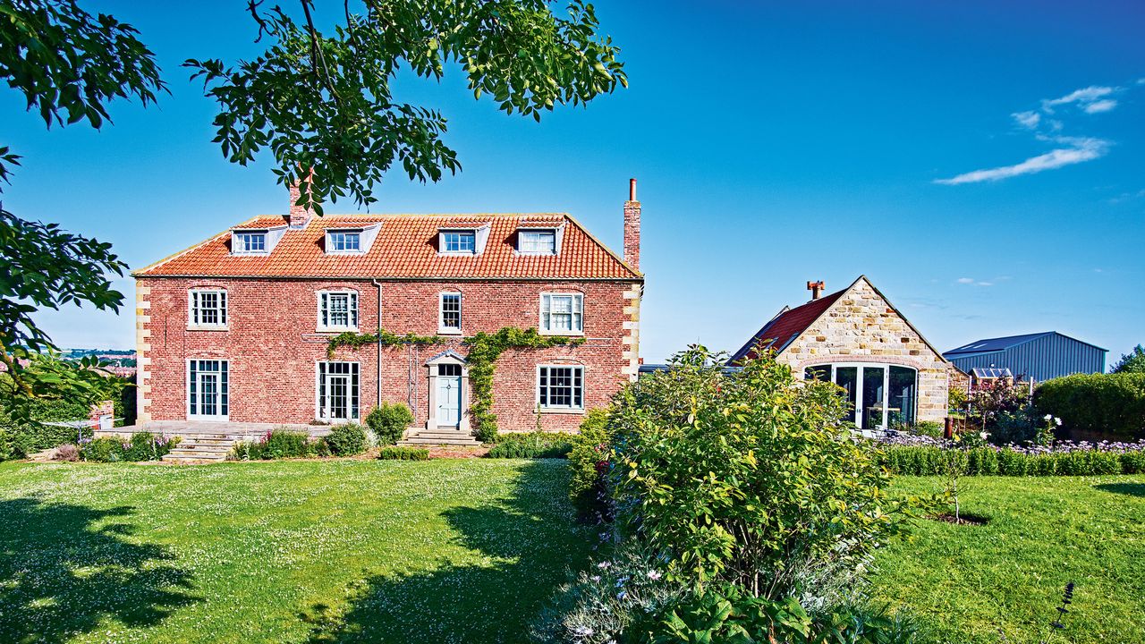 exterior of Georgian manor with extension lawn and blue sky