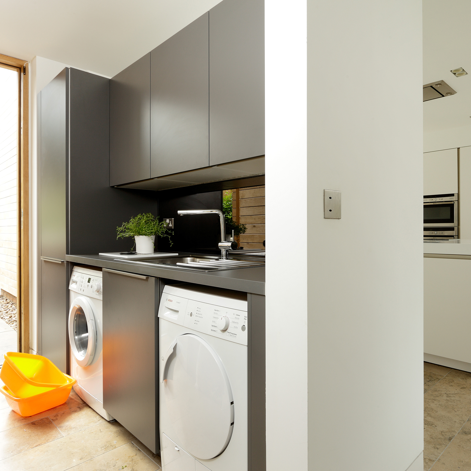 Broken plan kitchen utility room with sleek cabinetry and white appliances