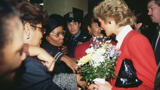Princess Diana in Harlem New York meeting a crod of people with a bouquet of flowers in her hand