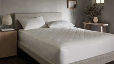Bed in a neutral room with a mattress protector on