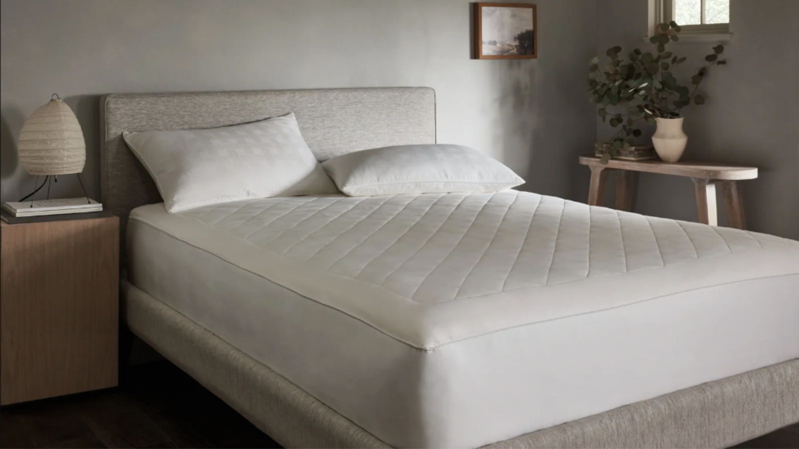 Bed in a neutral room with a mattress protector on