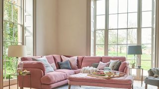 full height sash windows in living room with pink sofa