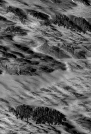 Martian terrain with dark streaks interpreted as avalanches blasted by shockwaves from a meteorite impact are visible in this photo from NASA's Mars Reconnaissance Orbiter.