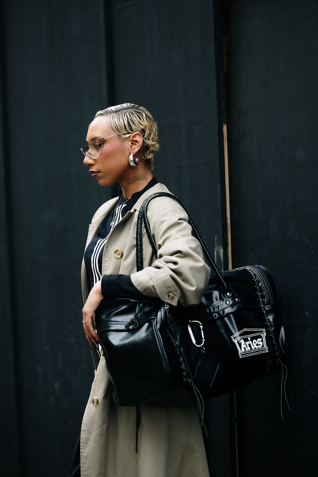 A woman with a cropped blonde bixie haircut, worn slicked back