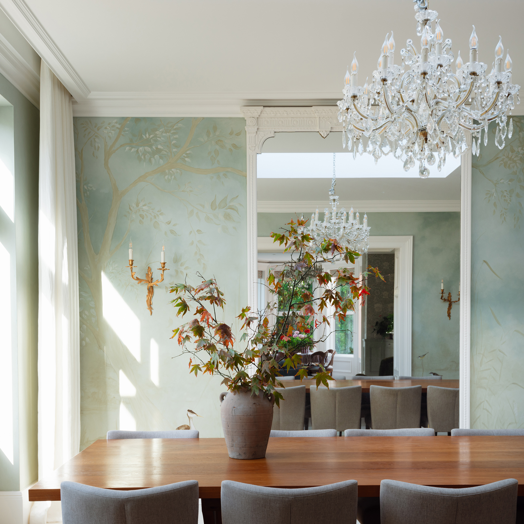 dining room with handpainted wall mural, large mirror, chandelier and mid-century style dining table and chairs
