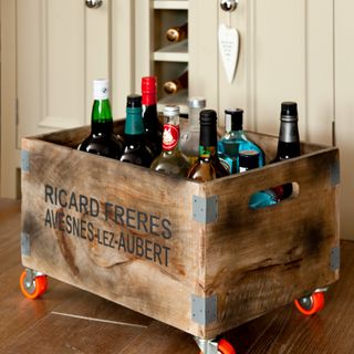 A wooden crate with bottles of alcohol in a kitchen